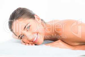 Beautiful brunette lying on massage table smiling at camera