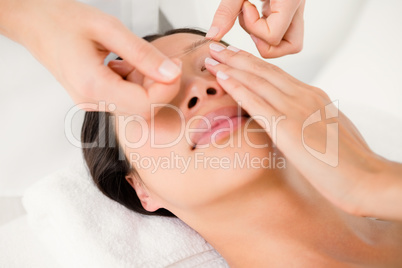 Hands threading beautiful womans eyebrow