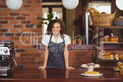 Smiling barista leaning on counter