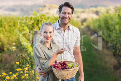 Two young happy vintners holding a basket of grapes