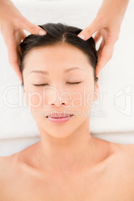 Attractive young woman receiving head massage at spa center