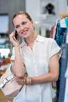 Smiling woman phoning next to clothes rail