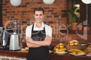 Smiling barista in front of counter with arms crossed