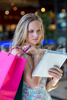 Woman with shopping bags using tablet computer