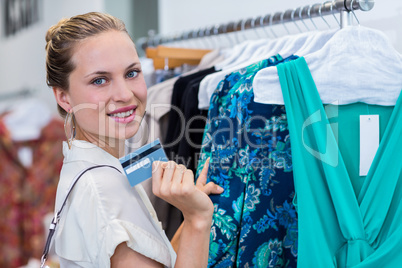 Smiling woman showing credit card to camera