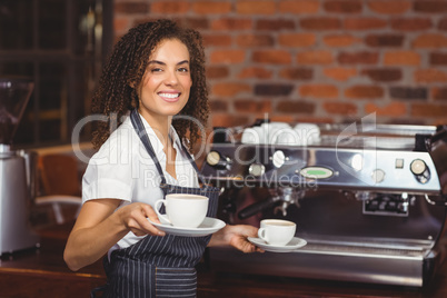 Smiling barista holding two cups of coffee