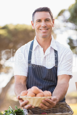 Smiling farmer holding a basket of eggs