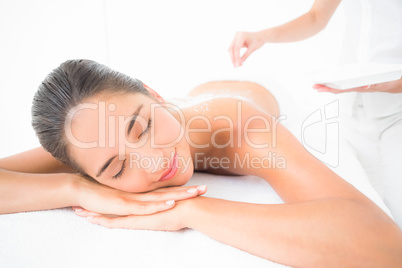 Beautiful brunette enjoying a salt scrub treatment