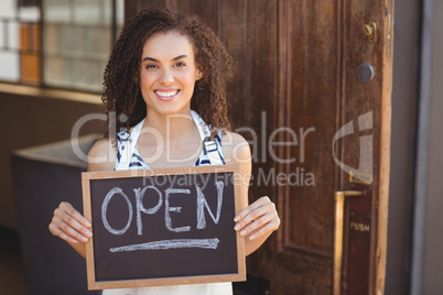 Smiling waitress showing chalkboard with open sign