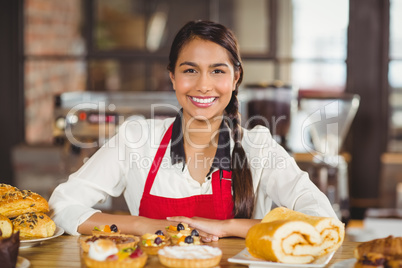 Smiling waitress standing over pastries
