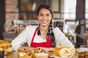 Smiling waitress standing over pastries