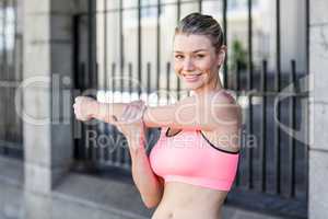 A beautiful woman stretching her arm against a fence