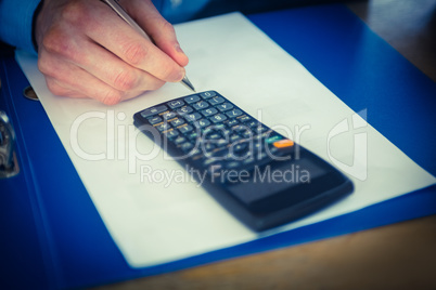 Businessman using a calculator and writing Businessman using a calculator and writing