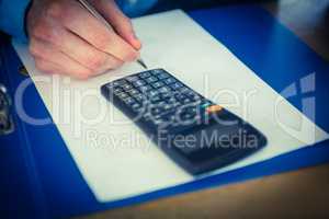 Businessman using a calculator and writing