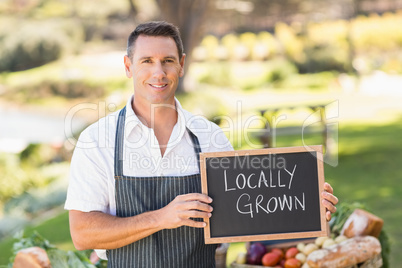 Smiling farmer holding a locally grown sign