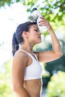 Tired athletic woman cooling forehead with water bottle