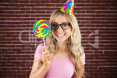 Portrait of a hipster with a party hat holding a lollipop