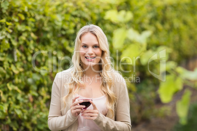 Young happy woman holding a glass of wine and looking at camera