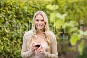 Young happy woman holding a glass of wine and looking at camera