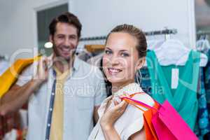 Smiling woman with shopping bags standing in front of her man