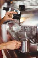Barista steaming milk at the coffee machine