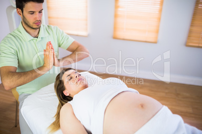 Relaxed pregnant woman getting reiki treatment