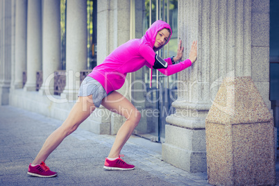 A woman wearing a pink jacket stretching