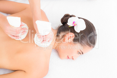 Beautiful brunette enjoying a herbal compress massage