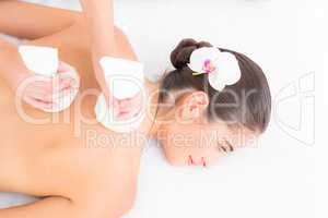 Beautiful brunette enjoying a herbal compress massage