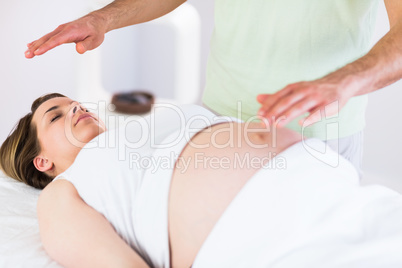 Relaxed pregnant woman getting reiki treatment