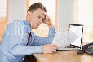 Focused businessman reading document at desk