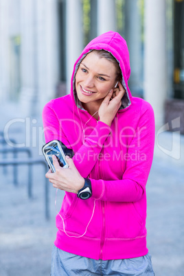 A woman wearing a pink jacket putting her headphones