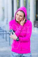 A woman wearing a pink jacket putting her headphones