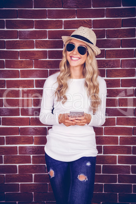 Gorgeous smiling blonde hipster holding smartphone