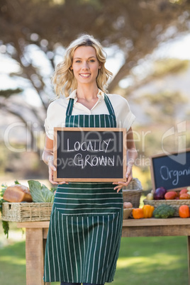 Smiling farmer woman holding a locally grown sign