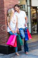Smiling couple with shopping bags leaning on the wall
