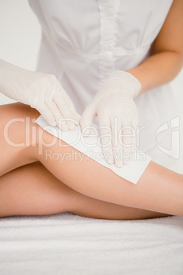 Therapist waxing womans leg at spa center