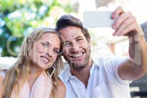 Smiling couple sitting and taking selfies