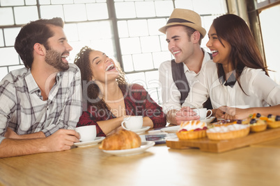Laughing friends enjoying coffee and treats