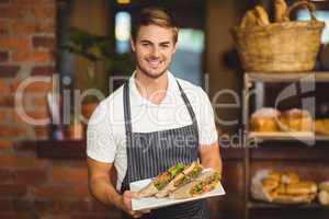Handsome waiter holding a plate of sandwiches
