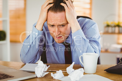 Stressed businessman with head in hands