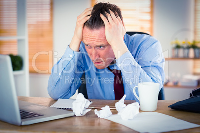 Stressed businessman with head in hands