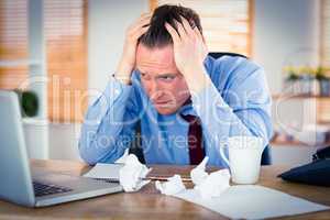 Stressed businessman with head in hands