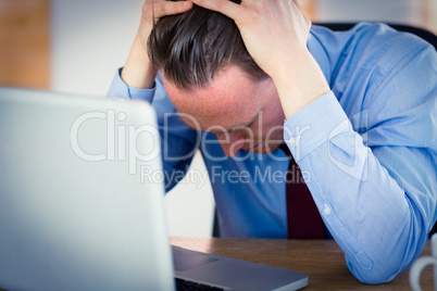 Stressed businessman with head in hands