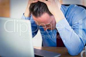 Stressed businessman with head in hands