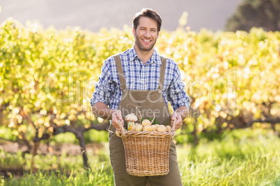 Smiling farmer holding a basket of potatoes