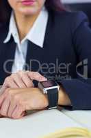 Businesswoman using her smartwatch at desk