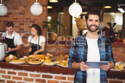 Smiling hipster using tablet in front of working barista