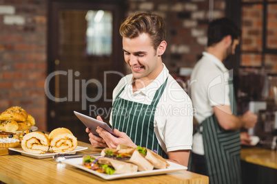 Smiling waiter using a digital tablet