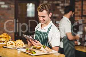 Smiling waiter using a digital tablet